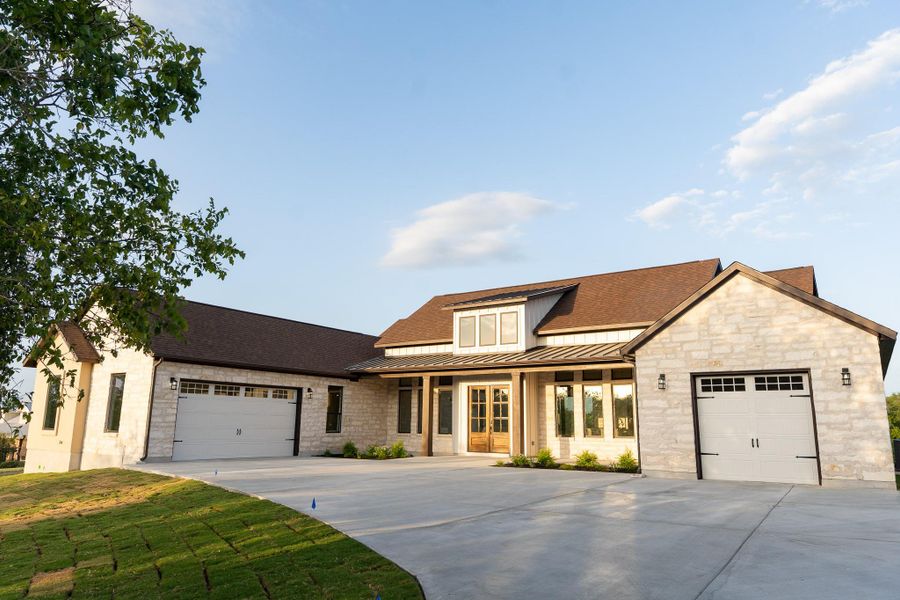 View of front facade featuring concrete driveway, a garage, a standing seam roof, and a metal roof View of front facade featuring concrete driveway, a garage, a standing seam roof, and a metal roof