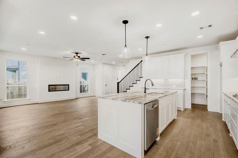 Open-concept living space with wood-finish flooring, a linear electric fireplace, and recessed lighting