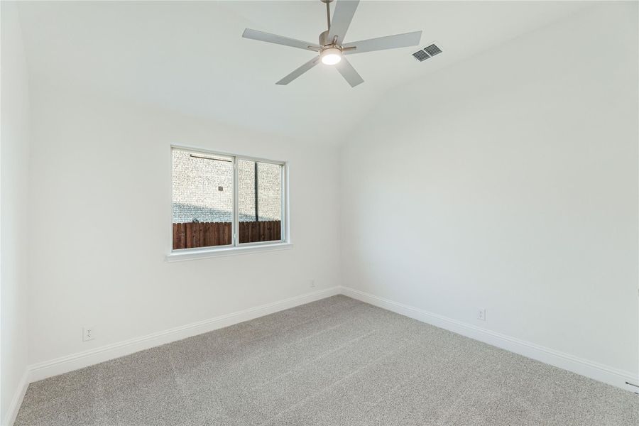 Empty bedroom with gray carpet, white walls, ceiling fan, and single window