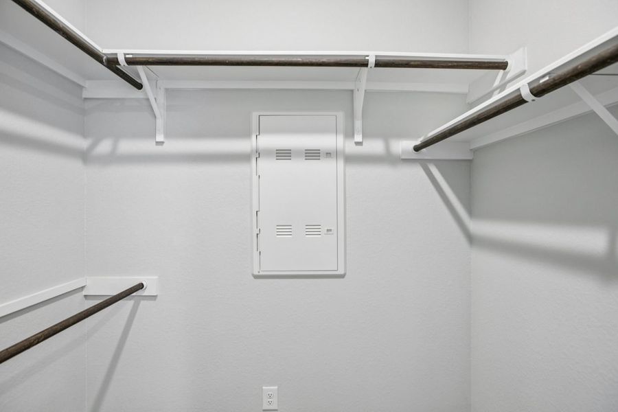 Image of the primary closet with light grey walls and wooden rods Image of the primary closet with light grey walls and wooden rods