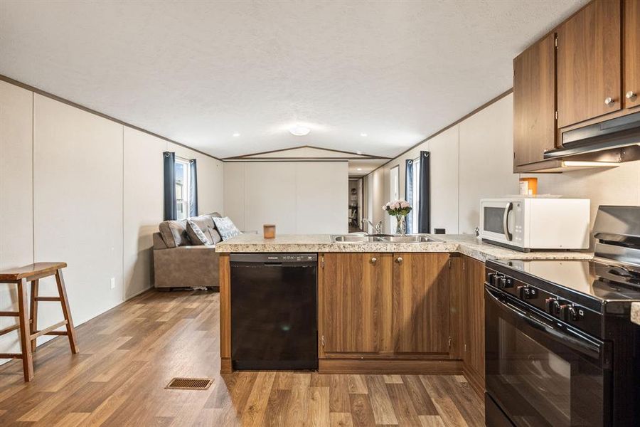 Kitchen featuring wood-finish cabinetry, speckled countertops, and a stainless steel sink Kitchen featuring wood-finish cabinetry, speckled countertops, and a stainless steel sink