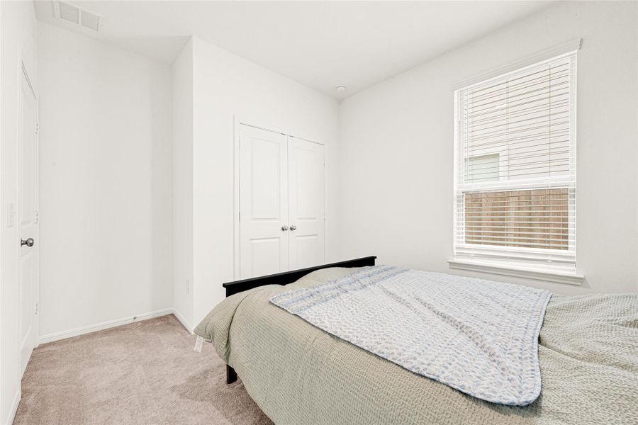 Cozy bedroom setup showing off the large window that brings in excellent natural light.