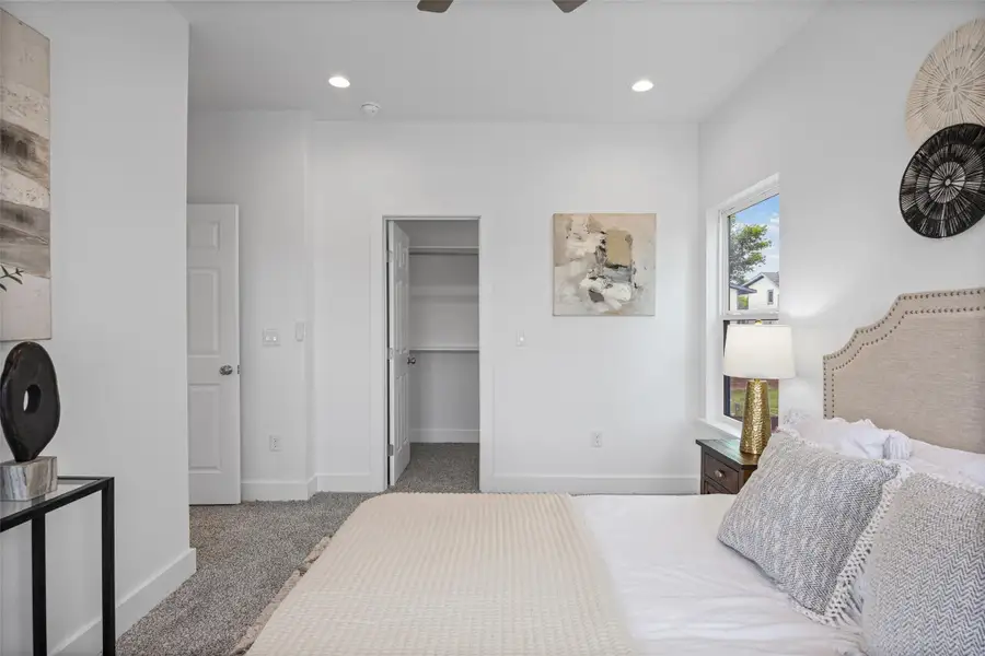 A well-lit primary bedroom offers plush carpeted floors and convenient closet access. A well-lit primary bedroom offers plush carpeted floors and convenient closet access.