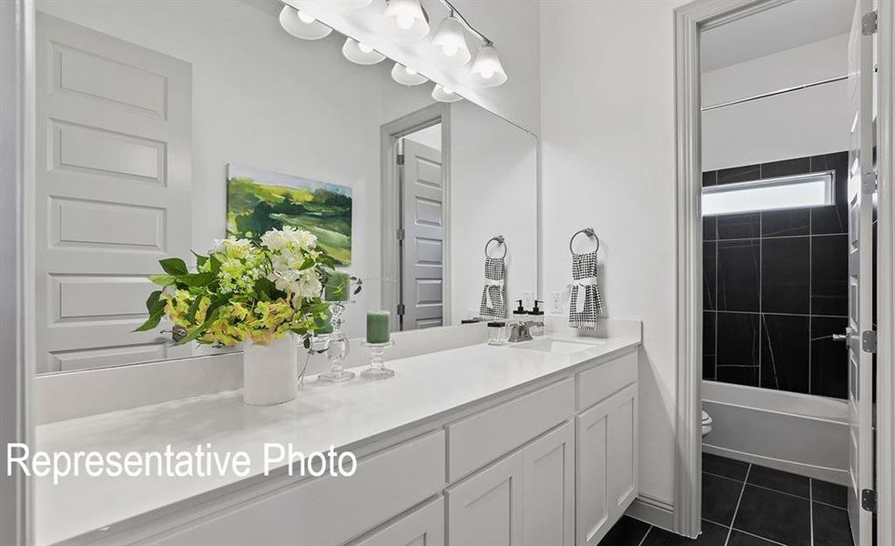 Full bathroom featuring vanity, toilet, tiled shower / bath combo, and tile patterned flooring