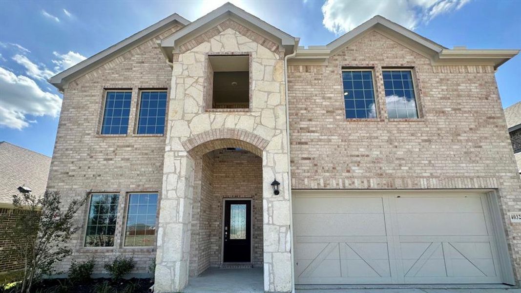 View of front of home featuring brick siding, a garage, and stone siding View of front of home featuring brick siding, a garage, and stone siding