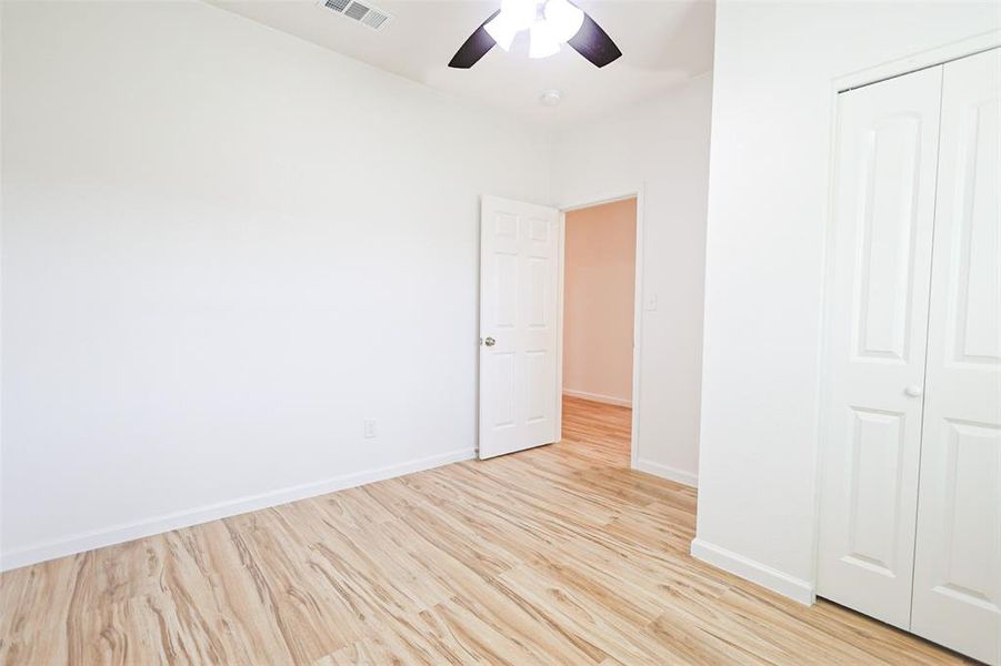 Unfurnished bedroom featuring light wood finished floors, a closet, and ceiling fan