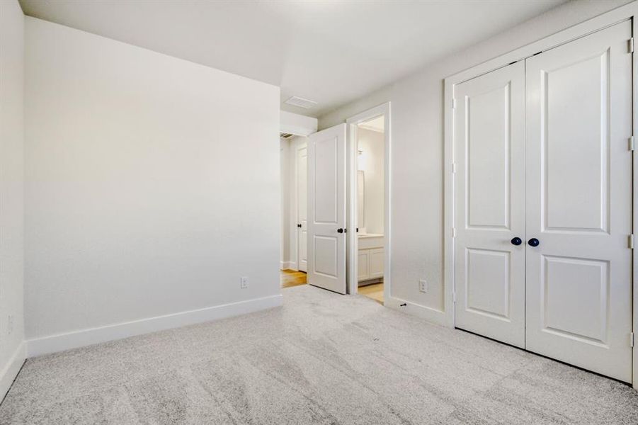 Unfurnished bedroom with light carpet, connected bathroom, and a closet