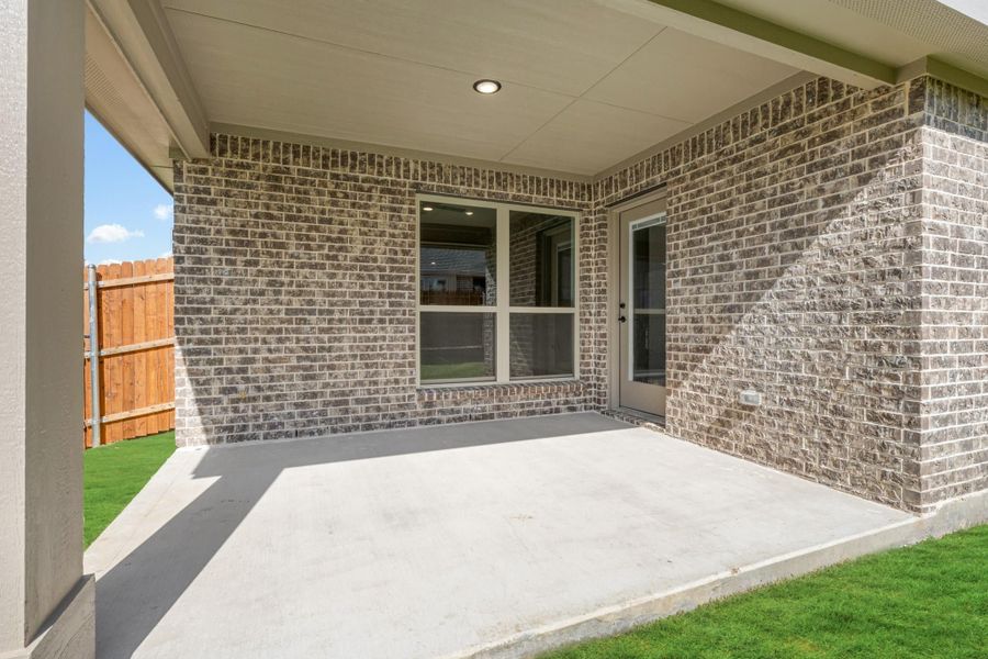 Covered back patio with concrete slab, brick exterior wall, and wood privacy fence Covered back patio with concrete slab, brick exterior wall, and wood privacy fence