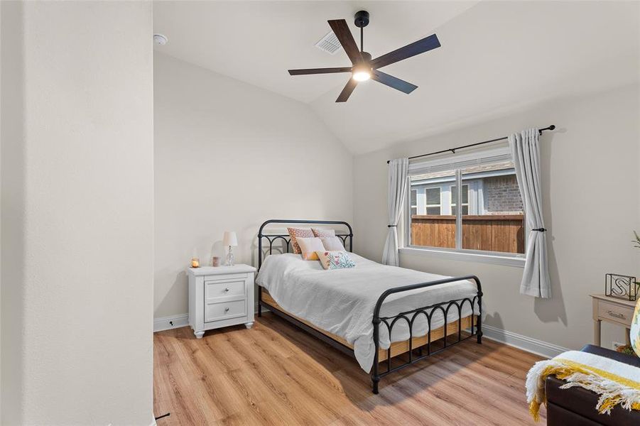 Bedroom featuring lofted ceiling, light wood-style flooring, and a ceiling fan Bedroom featuring lofted ceiling, light wood-style flooring, and a ceiling fan