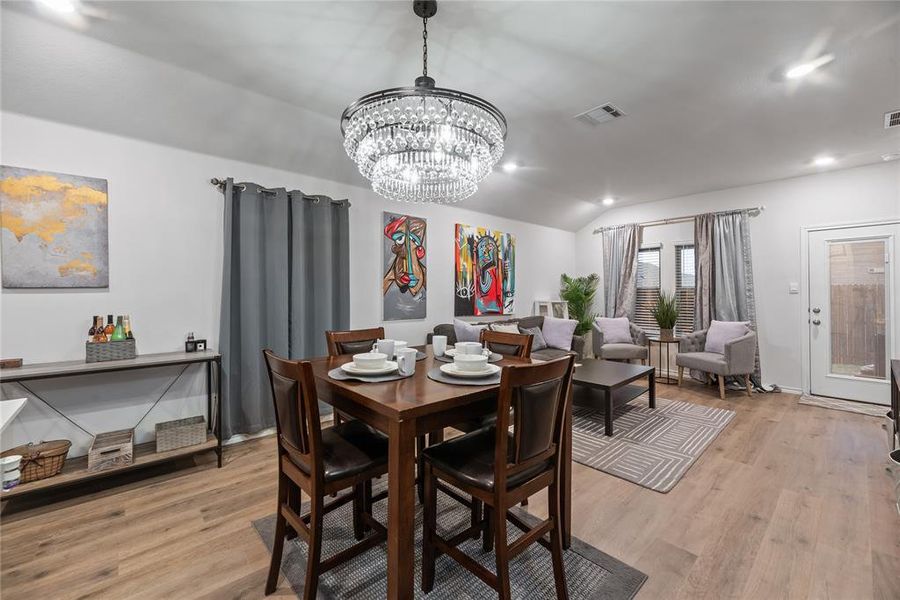Dining room with light wood-type flooring, lofted ceiling, a chandelier, and recessed lighting