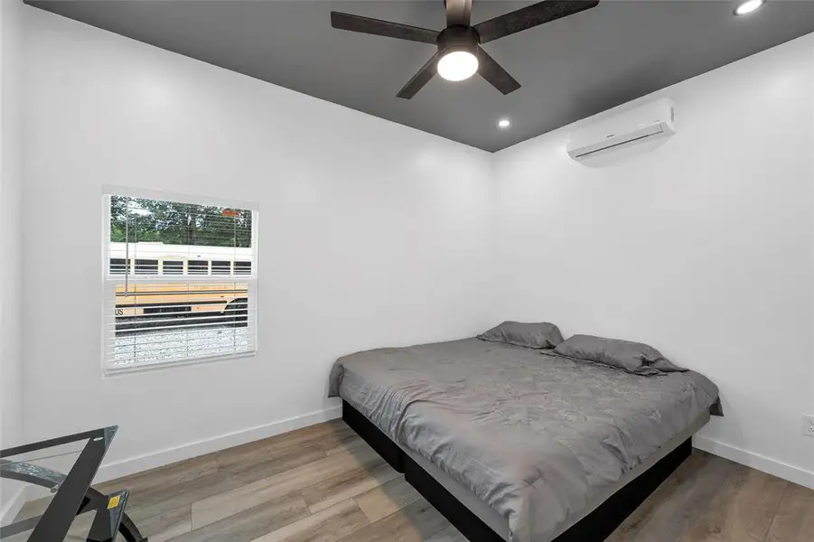 Bedroom featuring an AC wall unit, wood finished floors, recessed lighting, and a ceiling fan Bedroom featuring an AC wall unit, wood finished floors, recessed lighting, and a ceiling fan