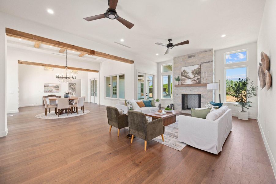 Living area with a ceiling fan, beamed ceiling, a fireplace, wood finished floors, and recessed lighting