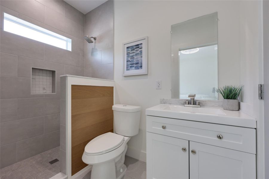 En suite bath for bedroom one features a clerestory window in the walk-in shower, custom wood accents and a Quartz counter. Closet doors are to the right of the vanity cabinet. En suite bath for bedroom one features a clerestory window in the walk-in shower, custom wood accents and a Quartz counter. Closet doors are to the right of the vanity cabinet.