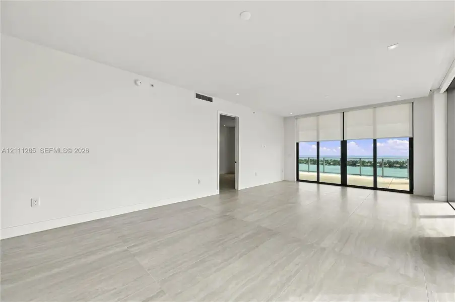 Neutral-toned stone flooring, recessed ceiling lighting, floor-to-ceiling glass sliding doors, and private exterior balcony Neutral-toned stone flooring, recessed ceiling lighting, floor-to-ceiling glass sliding doors, and private exterior balcony