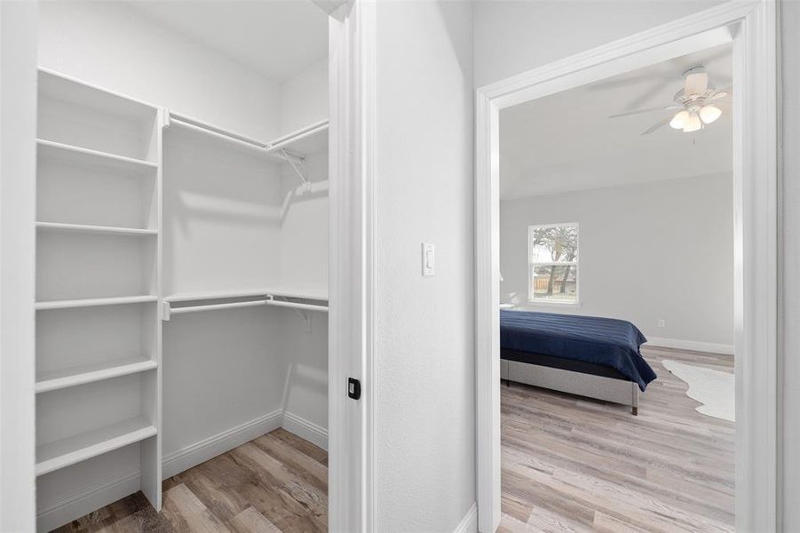 Walk in closet with light hardwood / wood-style flooring and ceiling fan