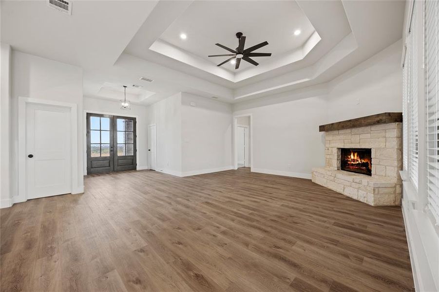 Unfurnished living room featuring ceiling fan, french doors, a stone fireplace, wood finished floors, and recessed lighting