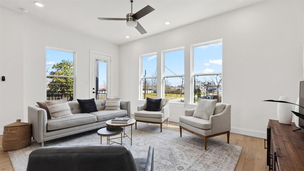 Step into the bright second-level living room, featuring hardwood floors, a ceiling fan, and recessed lighting. French doors lead to a private balcony, enhancing the room's airy ambiance.