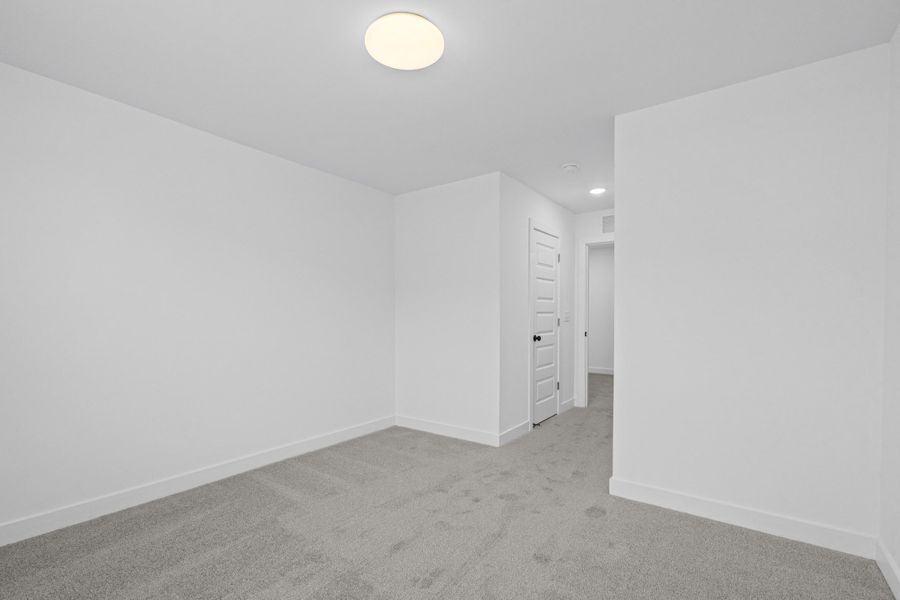 Neutral-toned room featuring a light gray carpet, white walls, and a contemporary flush-mount ceiling light