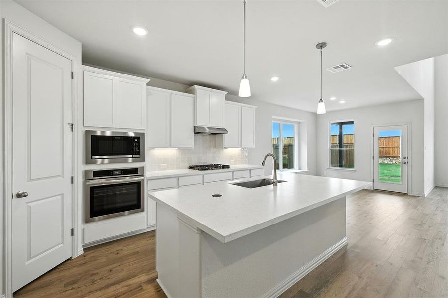 Kitchen with white cabinets, tasteful backsplash, stainless steel appliances, light countertops, and dark wood-style floors
