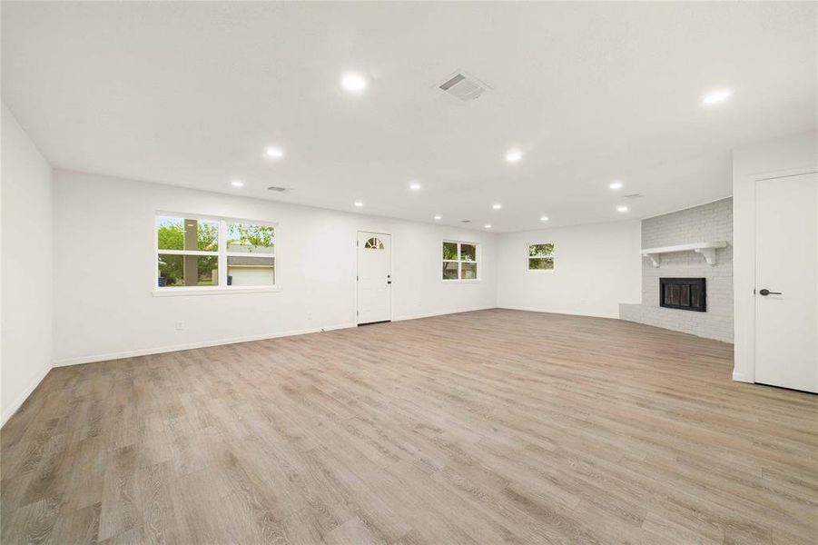 Unfurnished living room featuring light wood-type flooring, a fireplace, and recessed lighting Unfurnished living room featuring light wood-type flooring, a fireplace, and recessed lighting