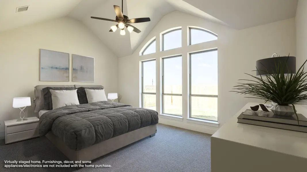 Carpeted bedroom featuring ceiling fan and high vaulted ceiling