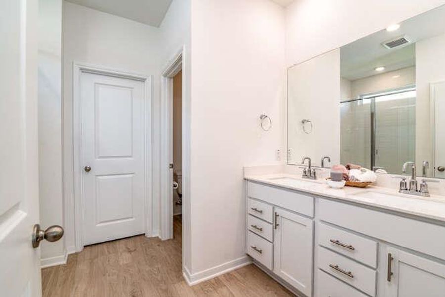 Bathroom featuring double vanity, wood finished floors, and a shower stall
