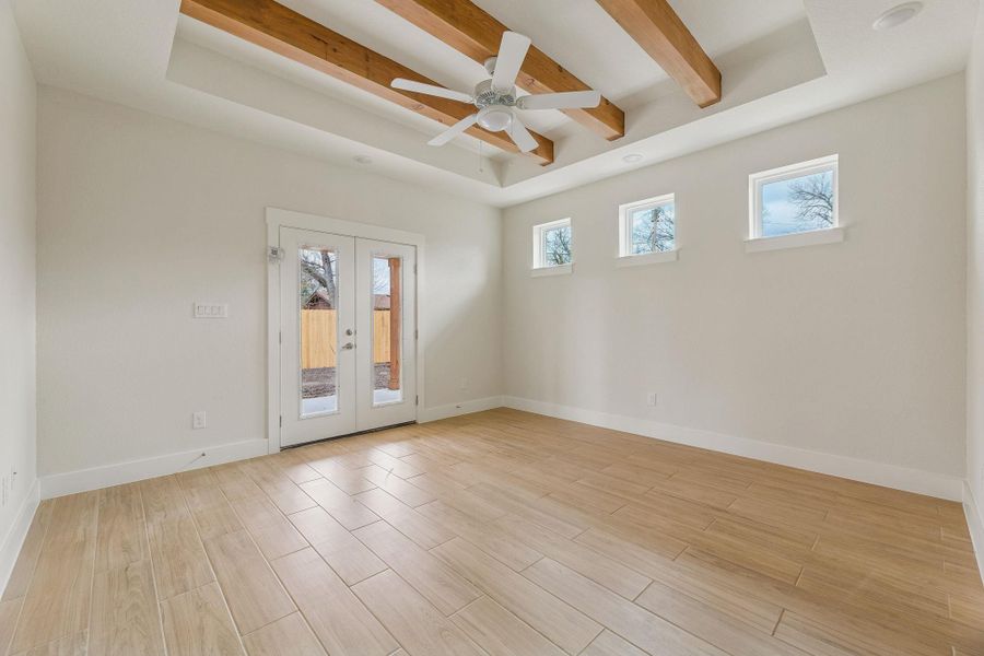 Primary bedroom with double doors to back patio. Beamed ceilings with ceiling fan.