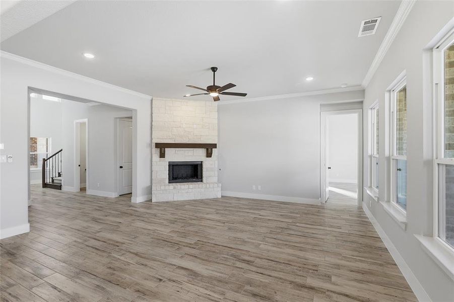 Unfurnished living room featuring a fireplace, a ceiling fan, recessed lighting, light wood finished floors, and crown molding
