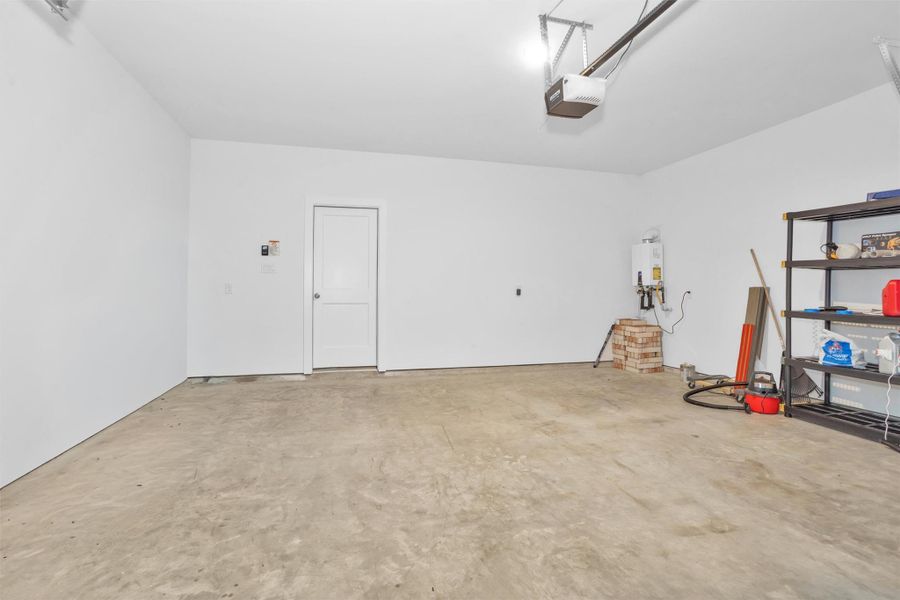 This spacious two-car garage features a tankless water heater, concrete flooring, and ample room for parking, storage, and workshop needs.