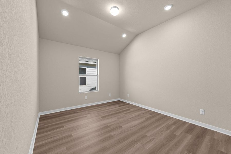 A well-lit bedroom features vaulted ceilings and rich wood-toned flooring, offering a fresh, adaptable space.