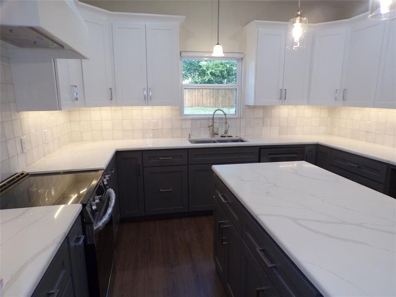 Kitchen featuring ventilation hood, hanging light fixtures, sink, and electric range oven