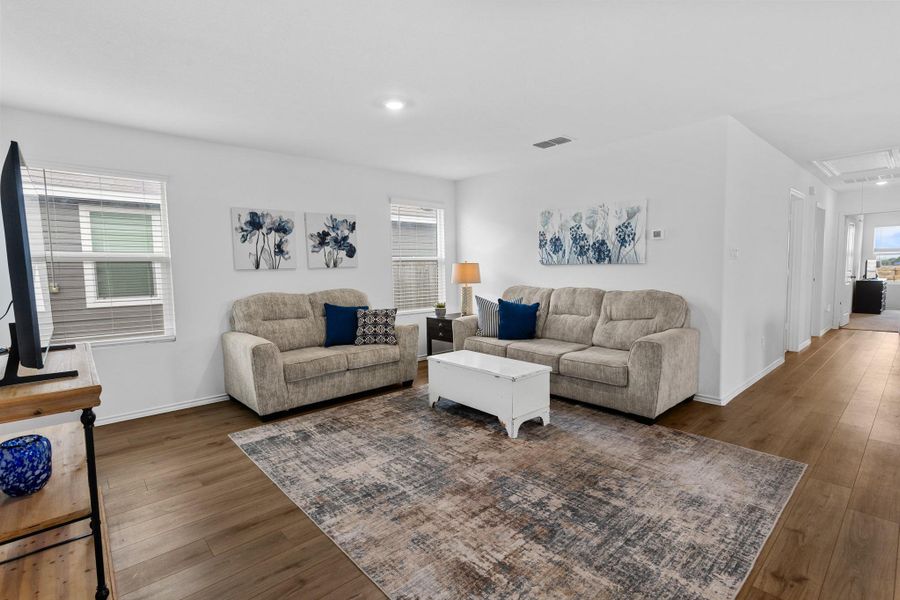 Spacious open-concept living area featuring wood-finish flooring, recessed lighting, and multiple windows