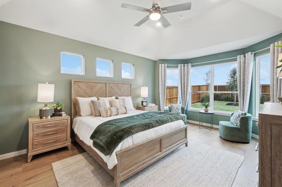 Bedroom featuring light wood-style floors, a ceiling fan, vaulted ceiling, and multiple windows