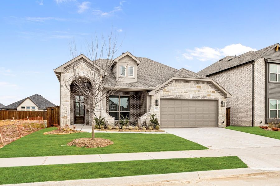 Single-story brick and stone home with arched entry, two-car garage, and manicured front lawn Single-story brick and stone home with arched entry, two-car garage, and manicured front lawn