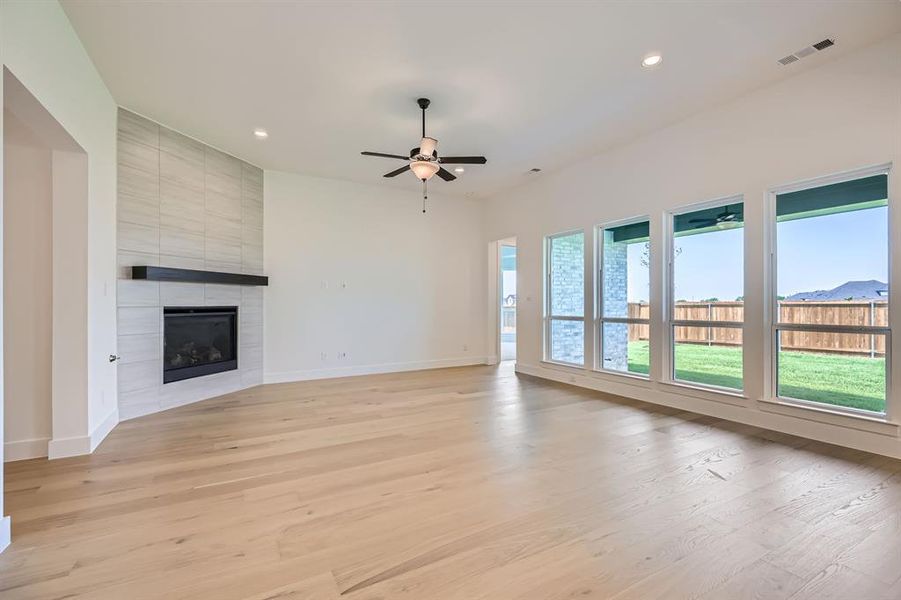 Unfurnished living room featuring a ceiling fan, a tile fireplace, baseboards, recessed lighting, and light wood-style floors Unfurnished living room featuring a ceiling fan, a tile fireplace, baseboards, recessed lighting, and light wood-style floors