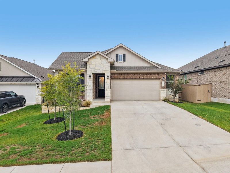 View of front of property with board and batten siding, concrete driveway, brick siding, and a front lawn View of front of property with board and batten siding, concrete driveway, brick siding, and a front lawn