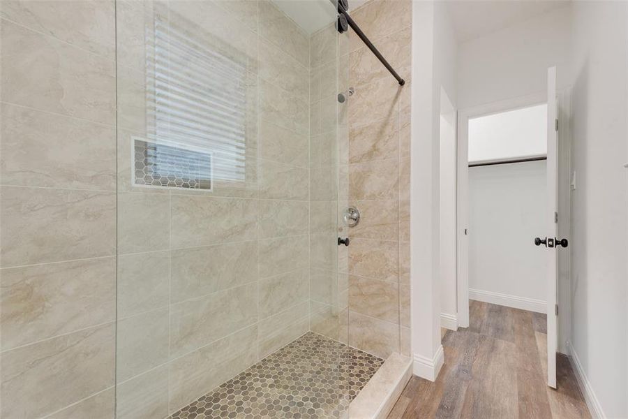 Bathroom featuring a tile shower and wood-type flooring