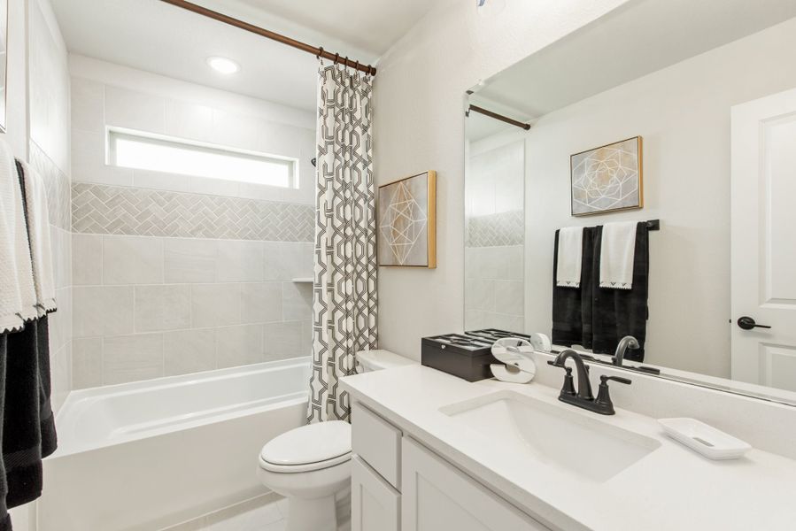 Bathroom with white vanity, tiled tub-shower combo with curtain, and toilet