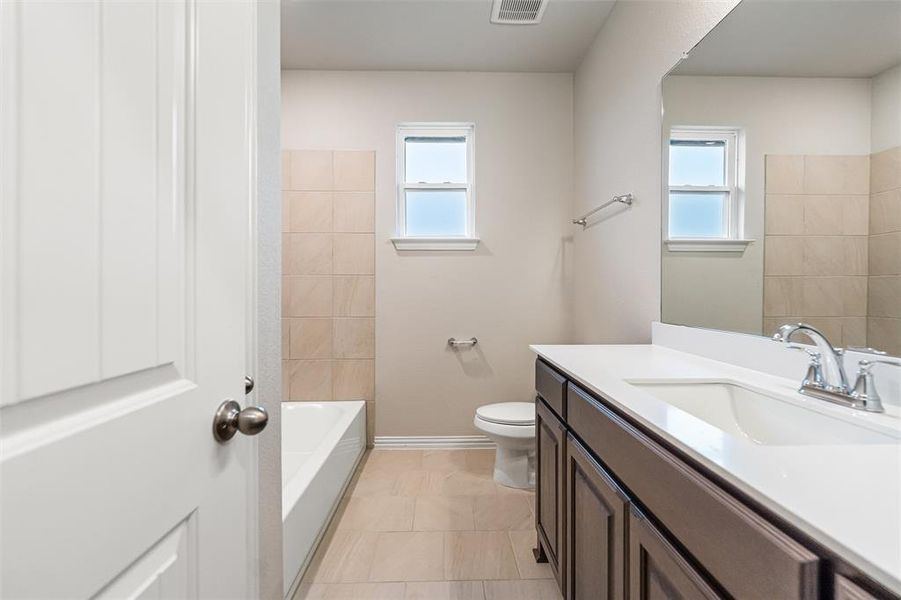 Bathroom featuring vanity, plenty of natural light, light tile patterned floors, and shower / tub combination