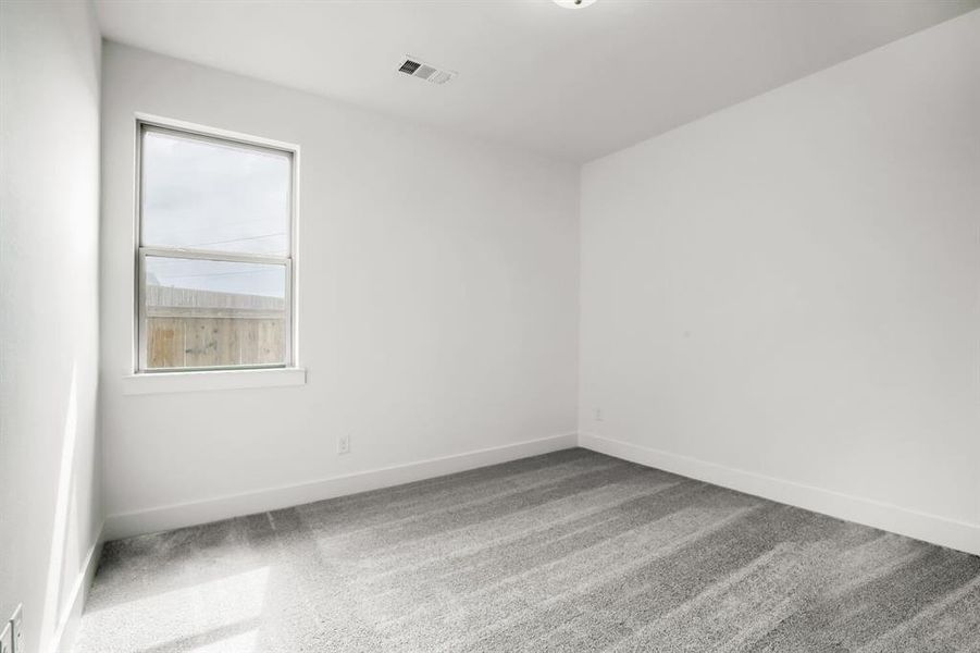 Bright interior space featuring a double-hung window, crisp white walls, and plush grey carpeting