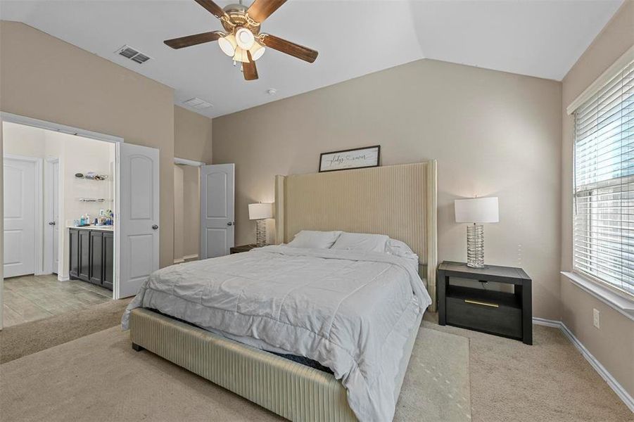 Carpeted bedroom featuring ceiling fan and vaulted ceiling