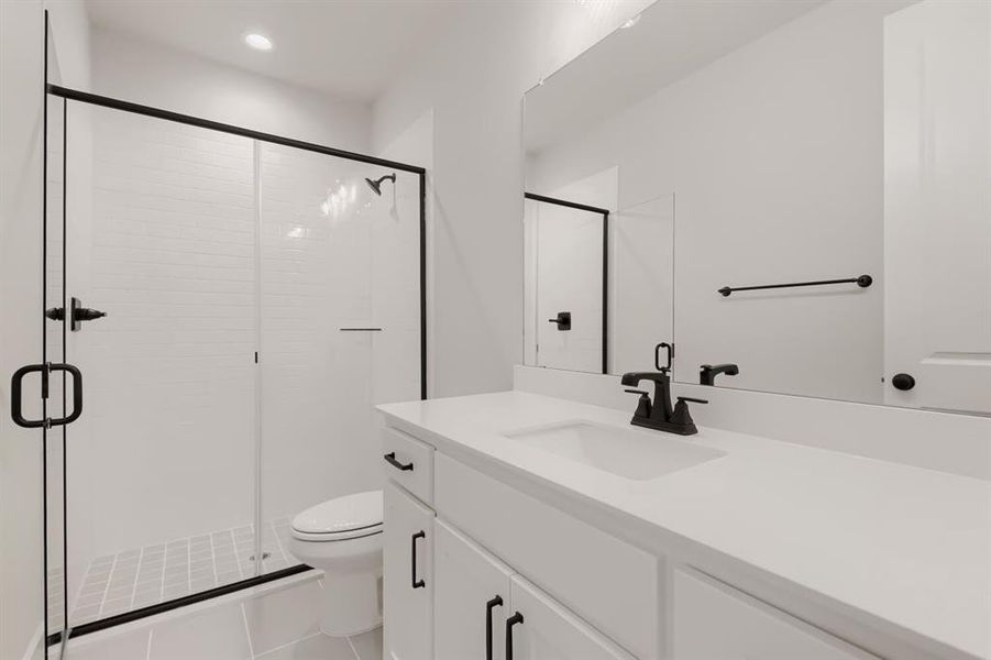 Contemporary bathroom featuring a walk-in shower with white subway tile, a frameless glass enclosure with matte black hardware, a pristine white vanity with an integrated sink, a matching countertop, and matte black fixtures