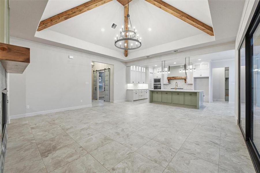 Unfurnished living room featuring a barn door, a chandelier, beamed ceiling, and recessed lighting Unfurnished living room featuring a barn door, a chandelier, beamed ceiling, and recessed lighting