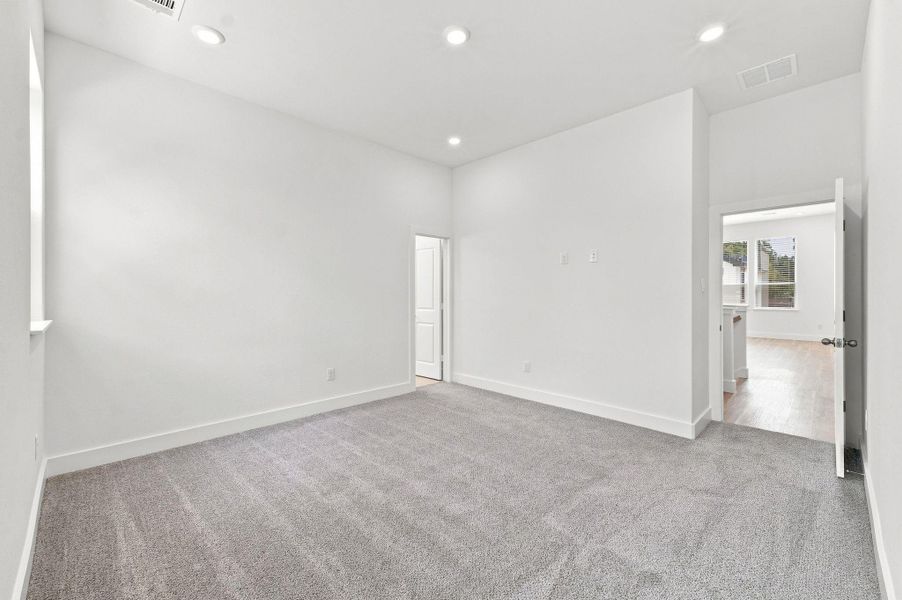 Another view of the primary suite highlighting its generous dimensions, high ceiling, and bright interior. Another view of the primary suite highlighting its generous dimensions, high ceiling, and bright interior.