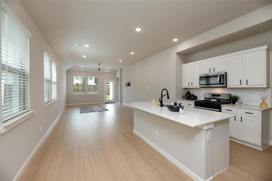 Kitchen featuring recessed lighting, an island with sink, gas range oven, ceiling fan, and stainless steel microwave Kitchen featuring recessed lighting, an island with sink, gas range oven, ceiling fan, and stainless steel microwave