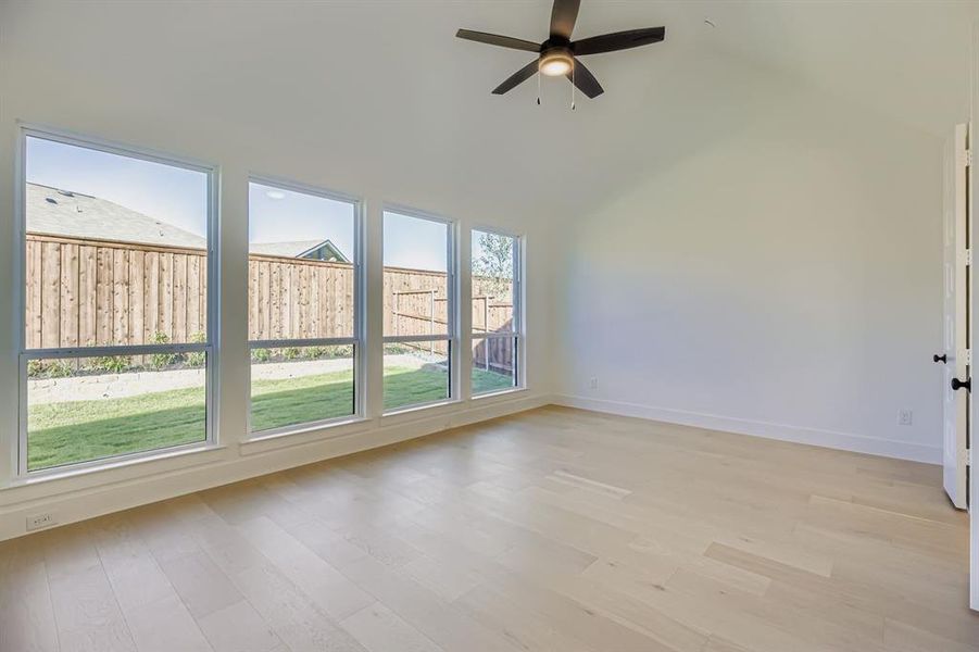 Unfurnished room featuring light wood-type flooring, ceiling fan, and vaulted ceiling
