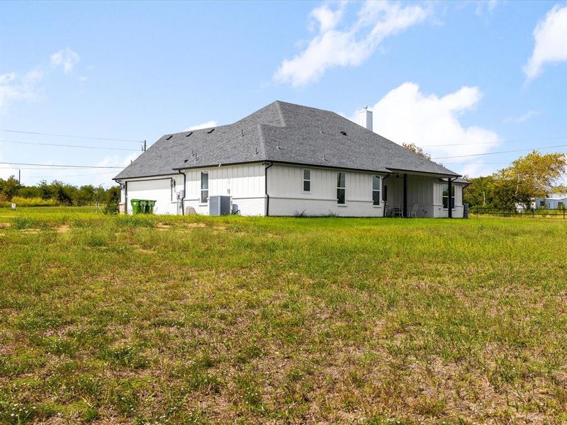 Rear view of property with a lawn, a shingled roof, a patio, and a chimney Rear view of property with a lawn, a shingled roof, a patio, and a chimney
