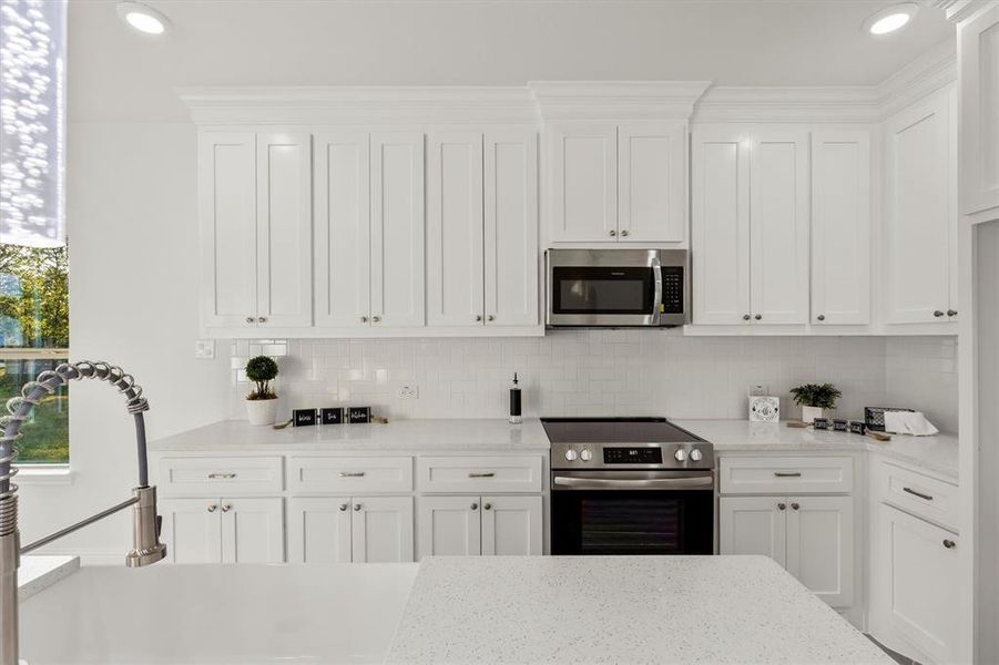 Kitchen with white cabinetry, a healthy amount of sunlight, appliances with stainless steel finishes, and decorative backsplash