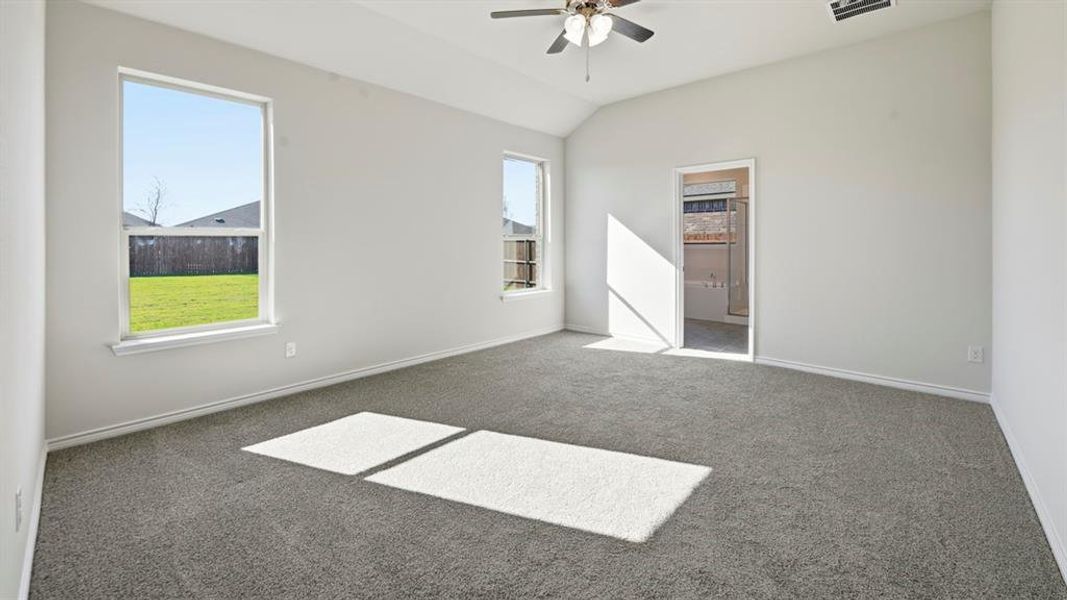Unfurnished bedroom with carpet, vaulted ceiling, ceiling fan, and ensuite bathroom