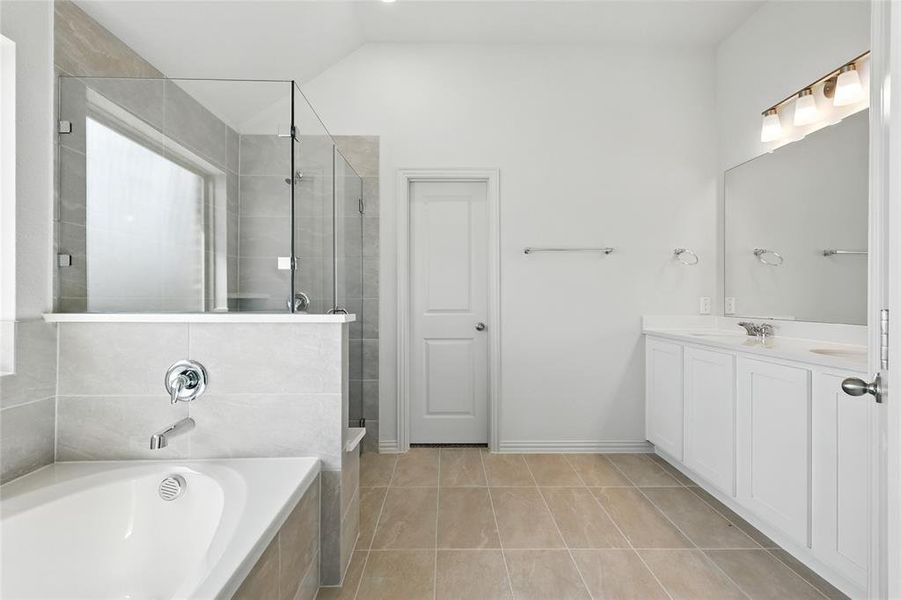 Bathroom with a shower stall, a garden tub, vanity, light tile patterned floors, and lofted ceiling Bathroom with a shower stall, a garden tub, vanity, light tile patterned floors, and lofted ceiling